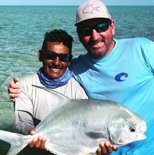 Image of George Grubb standing to the right of a guide holding a permit